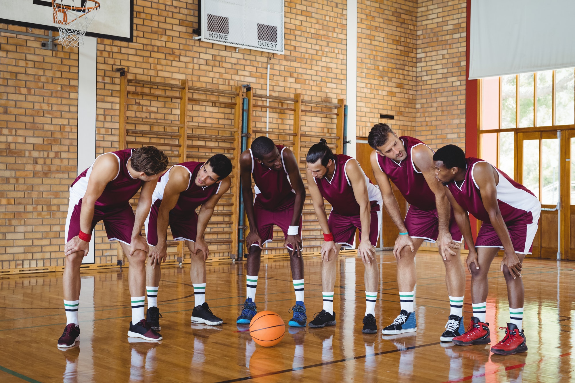 Eine Basketballmannschaft formiert sich in einer Linie auf dem Court, konzentriert und bereit.