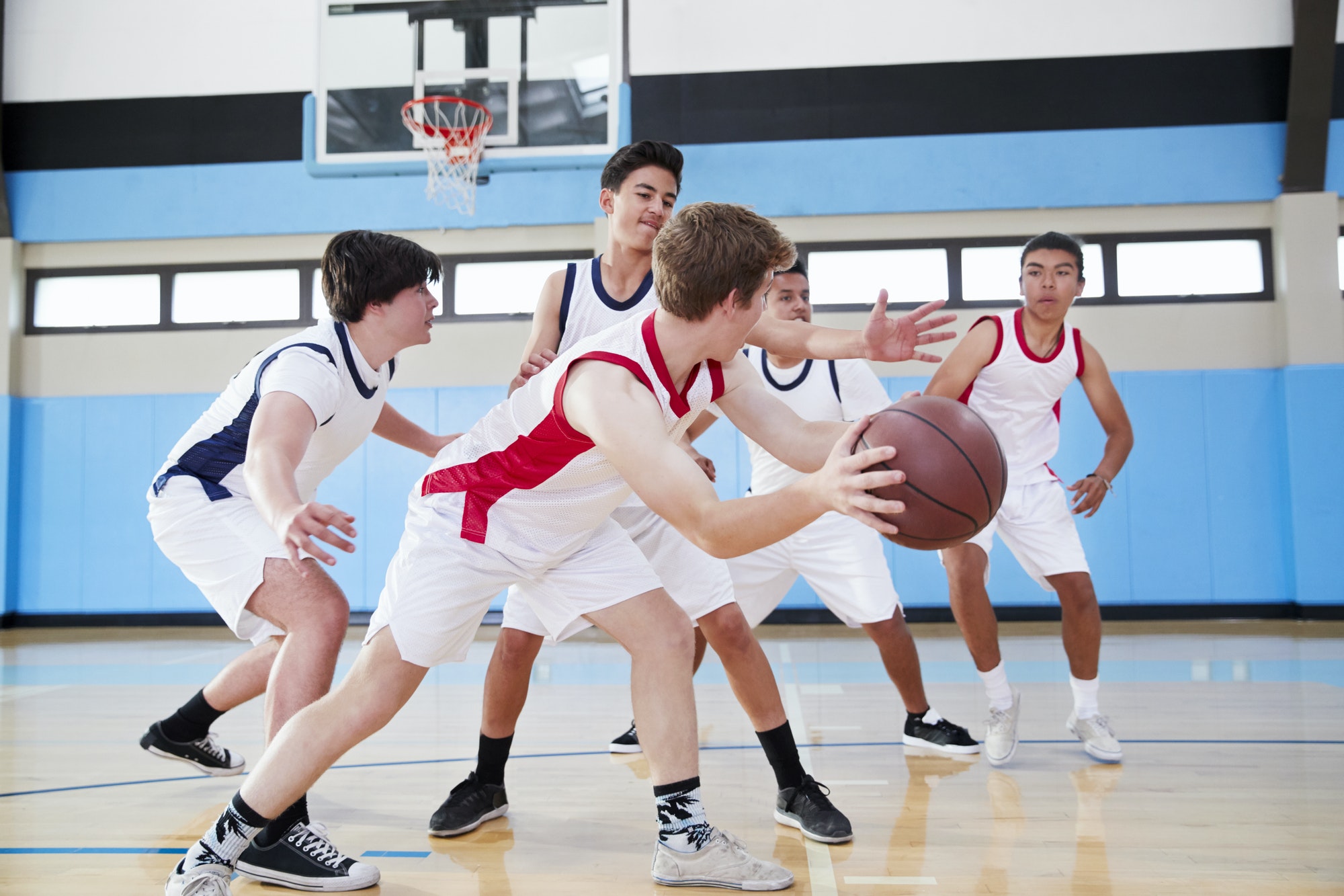 Junge Jungen spielen Basketball in einer Sporthalle.